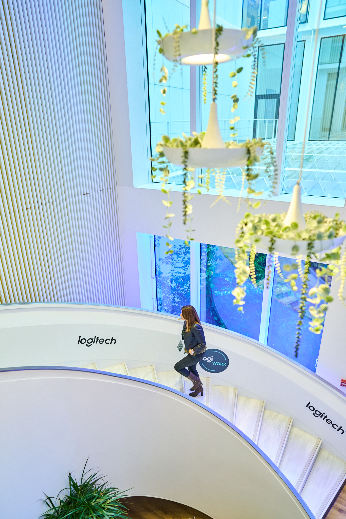 Fotógrafo corporativo en Madrid realizando reportaje de marca de la escalera y las instalaciones modernas de la oficina de Logi Work (Logitech). Muestra el diseño de facilities con iluminación azul.