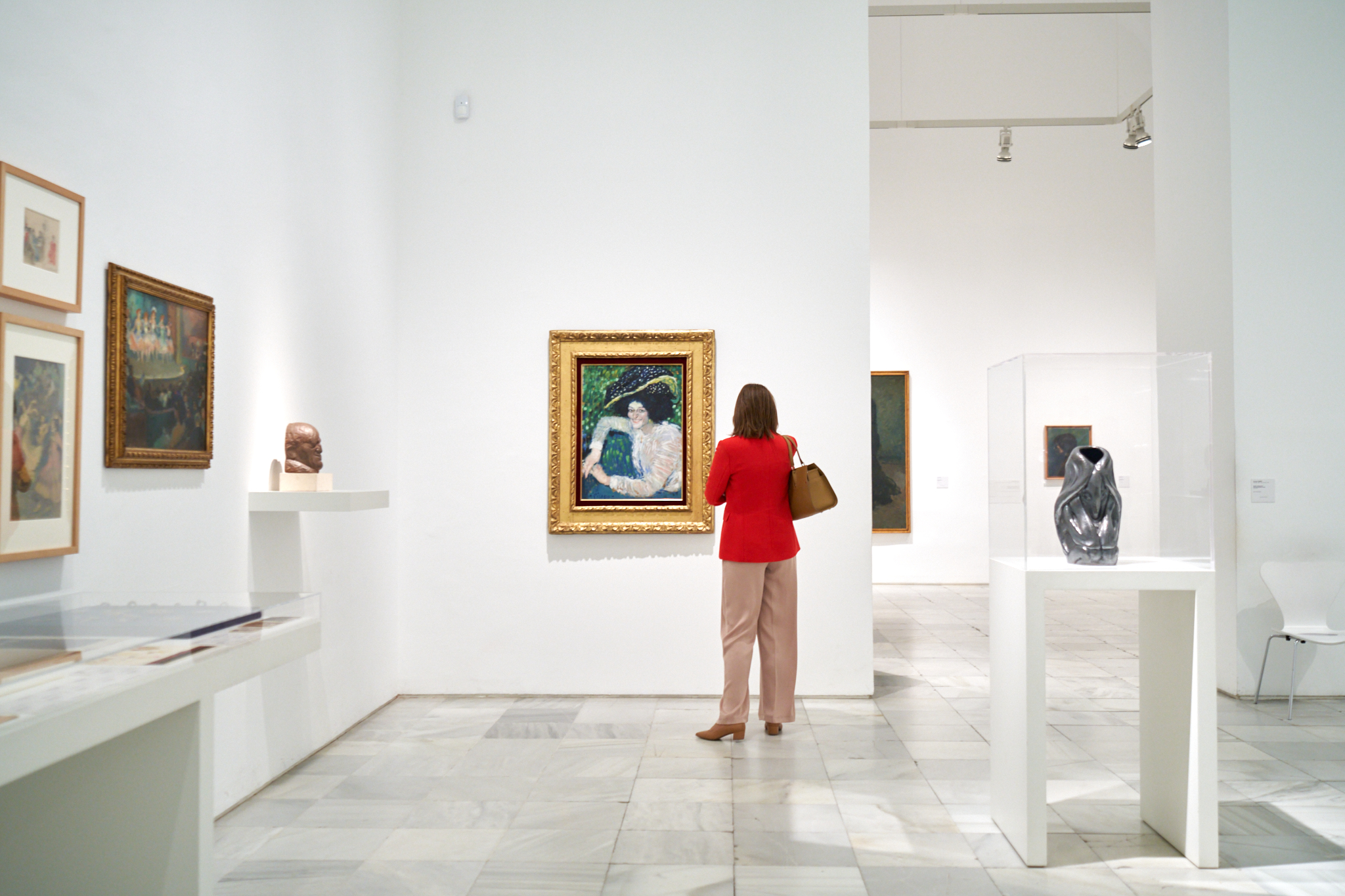 Fotografía de reportaje de empresa en Madrid. Fotógrafo profesional en Madrid capturando a una asistente en un evento o visita corporativa a un museo/galería de arte. Ideal para servicios de reportaje de marca e instalaciones en un contexto cultural.