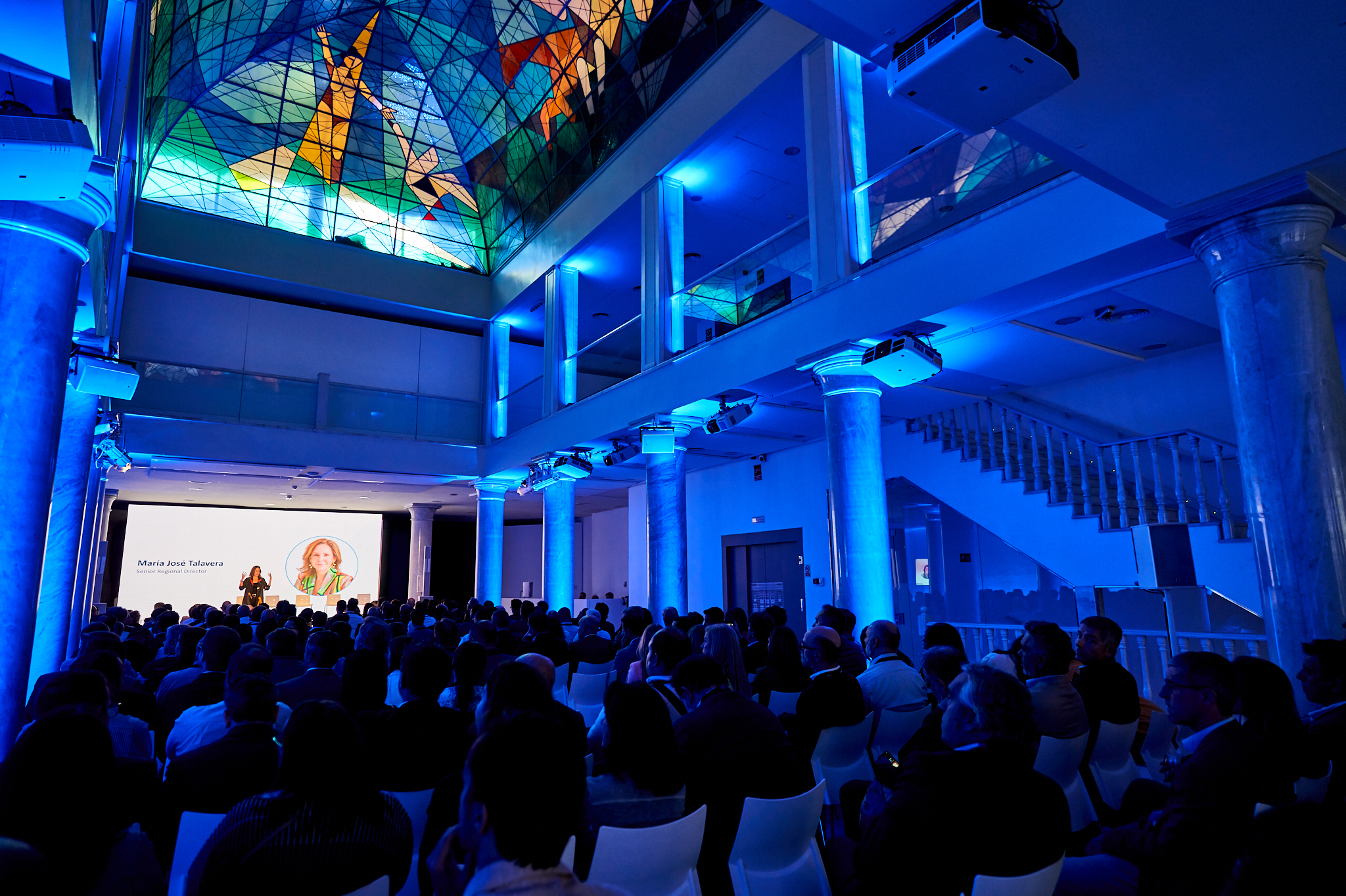 Fotografía de reportaje de gala y congreso de VmWare en Madrid. Fotógrafo profesional en Madrid cubriendo una jornada en un salón emblemático con vidrieras, destacando la ambientación en azul y la asistencia.