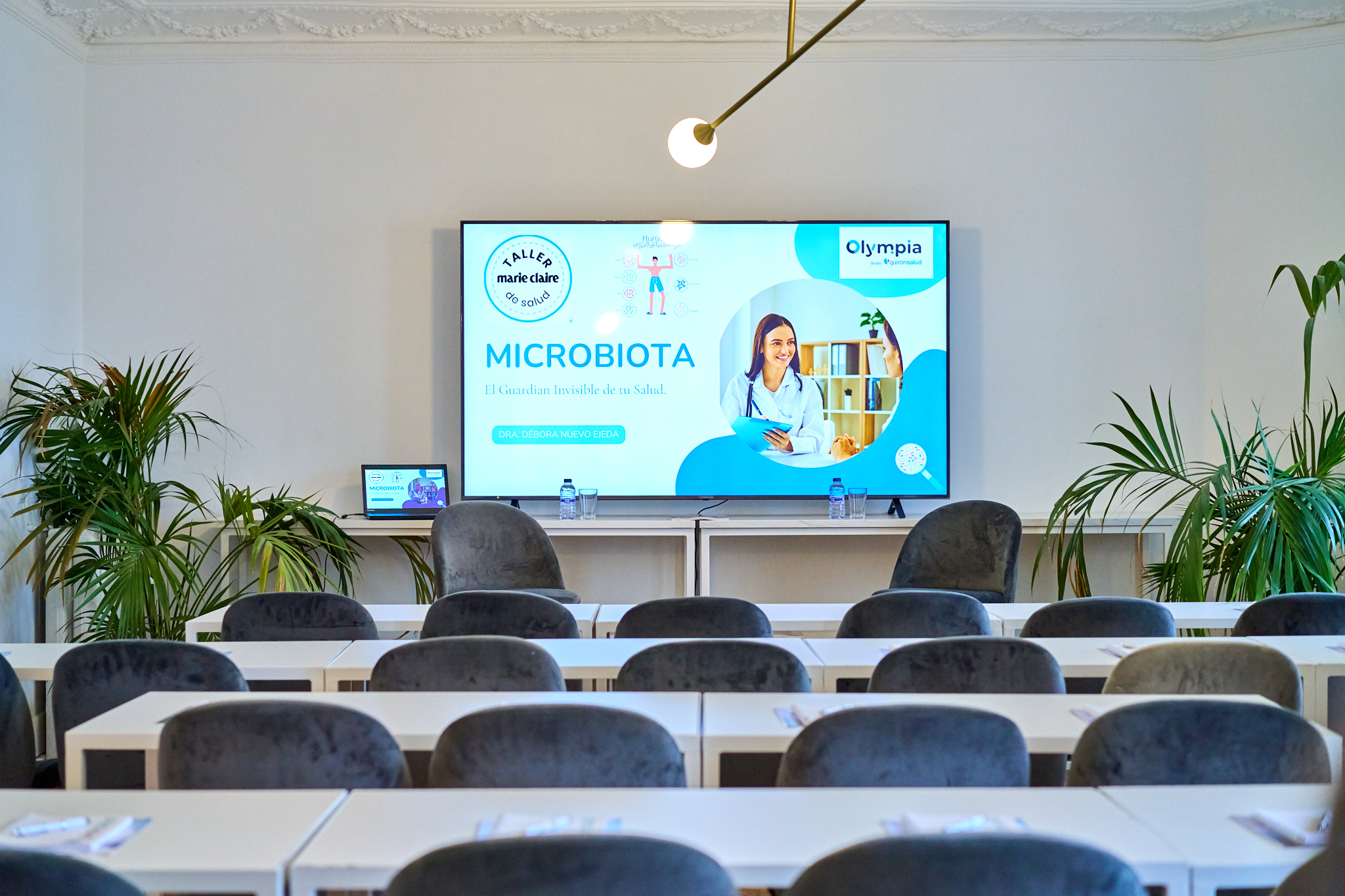Fotógrafo profesional en Madrid cubriendo un seminario o taller corporativo ("Taller Marie Claire de la Salud - Microbiota"). Muestra una sala con pantalla y marca. Ideal para fotografo para empresas en jornadas de formación.